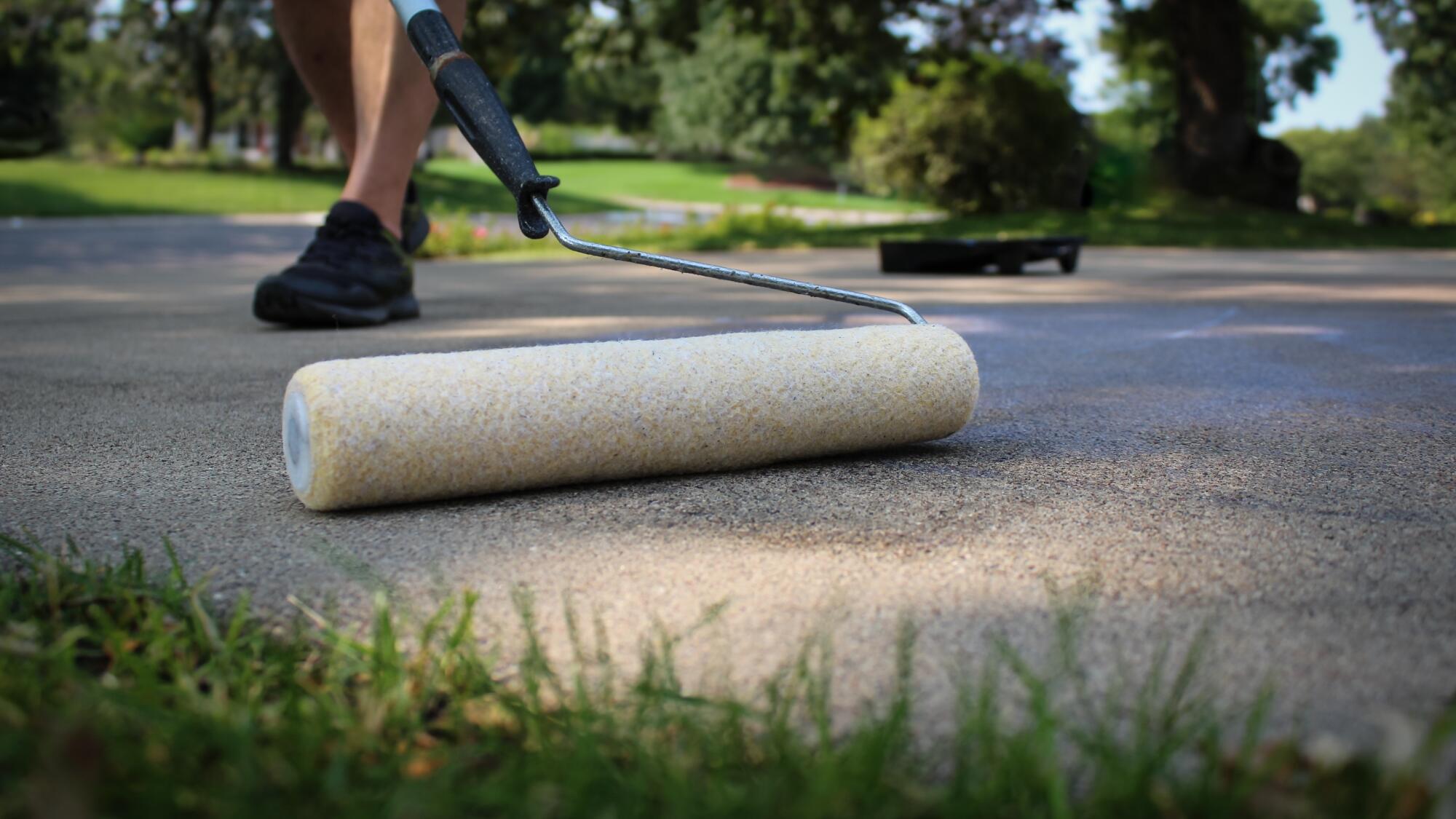 Expert at Chagrin Home Improvements applying sealant to a concrete driveway